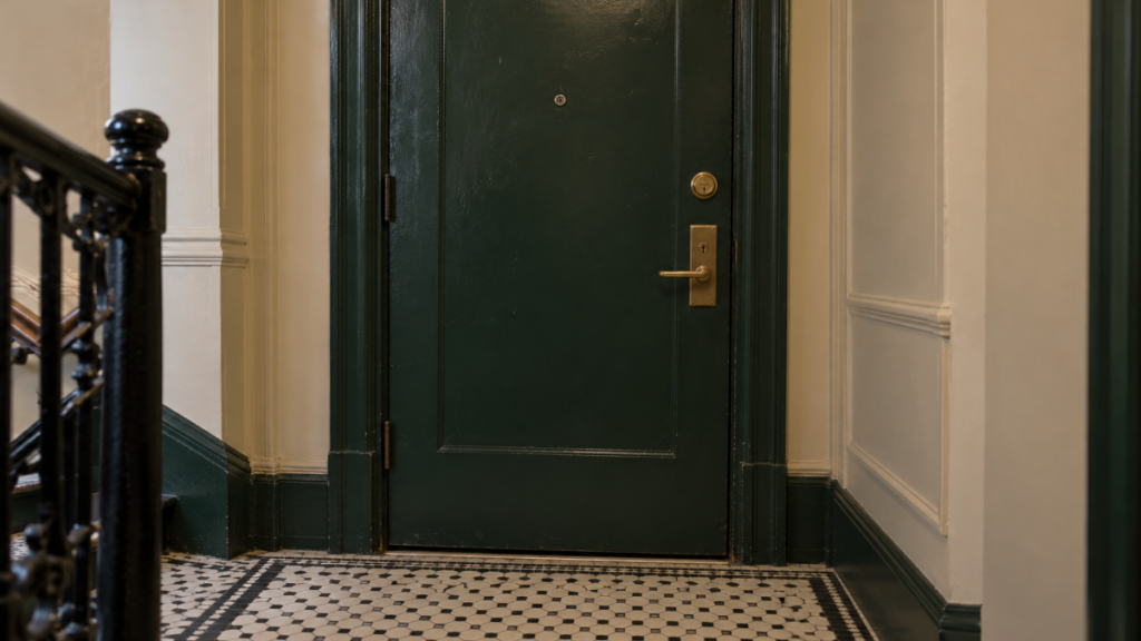Green apartment door with a deadbolt above a mortise lock with a brass lever and a peephole at eye level
